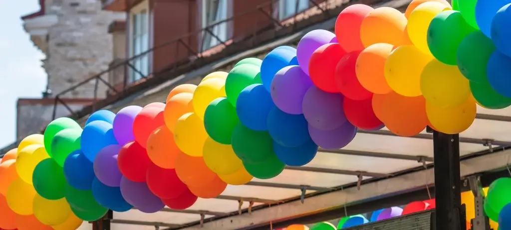Rainbow balloon arch decoration at an outdoor Pride parade or festival.