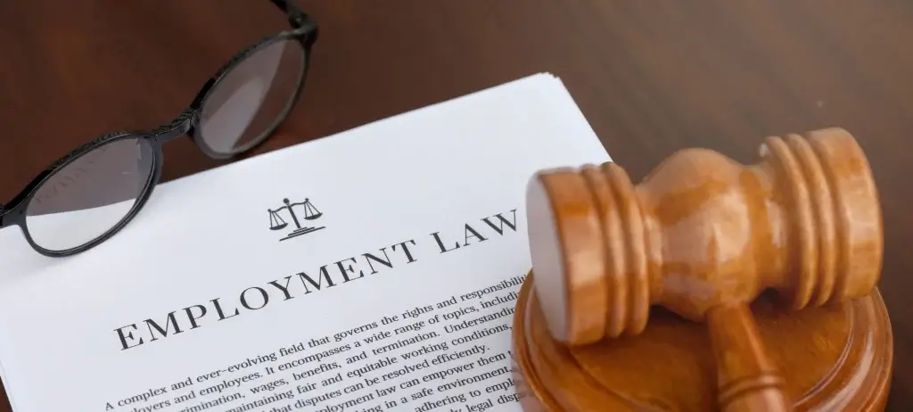 Close-up of an employment law document with a scales of justice icon, paired with a wooden judge's gavel and glasses, ideal for selecting an employment solicitor in Stoke on Trent.